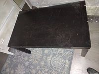 Black rectangular center or side table with scratches and surface wear on top.