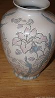 Photo showing the front side of the ceramic vase with lily flowers and algae in pastel colors
