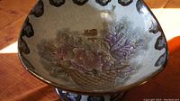 Close-up image of inside of Chinese pedestal bowl showing detailed floral artwork and scalloped edge