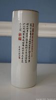 Porcelain holder showing vertical Chinese calligraphy with red seals on white glazed surface