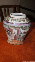 Chinese porcelain jar shown from front angle highlighting traditional figures, floral and architectural motifs on the surface