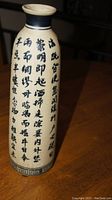 Tall Chinese vase with vertical black calligraphy on white background, dark blue neck and border at base.