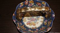 Top view of the floral decorative basket showing the intricate floral patterns inside the bowl along with the gold-tone handle.