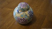Floral round jar on wooden surface showing overall design and shape
