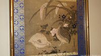 Woodblock print showing two quail birds among flowering plants with blue patterned borders