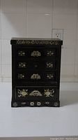 Small decorative wood jewelry box with metal floral inlays and multiple drawers