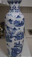 Front view of tall baluster porcelain vase showing overall hand-painted blue landscape scenes