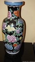 Front of large decorative vase showing multicolor floral design on black background with blue border rim