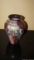 Front view showing the red purplish glossy vase with Asian character designs in gold and white.
