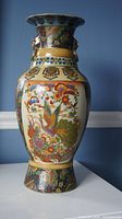 Front view of vase showing colorful bird and floral designs on cream background with ornamental bands.