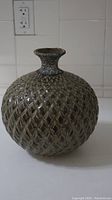 Front view of a round, textured ceramic jar showing diamond pattern and narrow neck