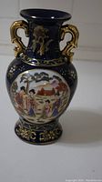 Front view showing the blue vase with gold handles and painted Asian figures and landscape