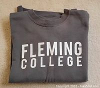 Folded grey sweatshirt with white text FLEMING COLLEGE visible on front.