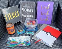 Photo showing three planner books and a notebook with Pokémon theme, assorted stationery items including paper clips, push pins, an eraser, a wrist cuff, colorful marker pack, and a sequin pouch.
