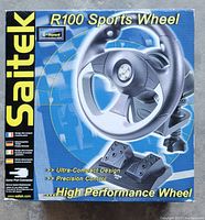 Photo of the Saitek R100 Sports Wheel product box showing the front with wheel and pedals illustrated, highlighting features such as ultra-compact design and precision control.
