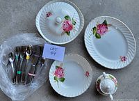 Photo shows multiple Swinnertons ironstone dishes with prominent pink rose floral designs and a set of assorted cutlery wrapped in bubble wrap, along with a lot number card.