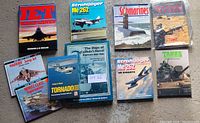 Overhead view showing all ten wartime military books arranged on a flat surface, titles clearly visible including Jet Warplanes, Strahljäger Me 262 (two copies), Submarines, Tanks, Harrier Jump Jet, Simitz Class Supercarrier, The Ships of Canada's Naval Forces 1900-1955, Tornado, and Strike Fighter Tornado.