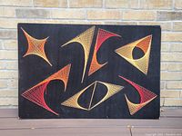 Front view of the vintage string art piece showing the entire artwork with geometric string designs on black wood background.