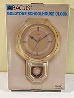Front of the boxed Abacus Goldtone Schoolhouse Clock showing the clock image and branding.