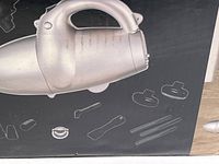Photo of the vacuum cleaner on the box artwork showing the main handheld vacuum unit and outlines of various attachments included.