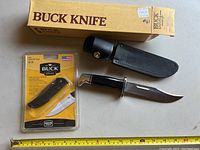 Overall view of both Buck knives: one fixed blade with sheath and one smaller Bantam BLW folding knife in original packaging.
