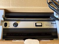 Unit resting in original foam inserts showing front control panel, speaker, antenna and AC cord