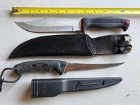 Kershaw fixed blade knife with black rubber handle and leather sheath plus American Angler fish cleaning tool with plastic sheath