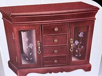 Front view of the wooden jewelry box with walnut finish showing etched glass doors, drawers, handles, and decorative details.