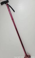 Full length view of red adjustable Hurrycane cane showing entire shaft and handle.