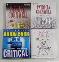 Front covers of four factory sealed audiobooks on CD format laid out to show titles and authors.