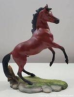 Front and side view of the red pony figurine showing detailed pose and paintwork mounted on grass and rock base.