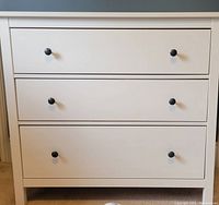 Front view of white IKEA Hemnes 3-drawer dresser with black round knobs.