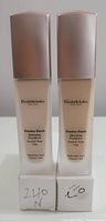 Front view of two Elizabeth Arden Flawless Finish Foundation bottles with rose gold caps, showing product name and shade numbers 240N and 120N on white boxes below.