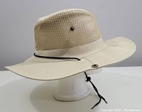 Side view of beige Tilley style mesh hat showing wide brim, mesh crown and chin strap