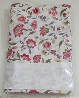 Full view of the folded tablecloth in its packaging showing the floral pattern clearly.