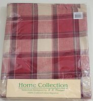 Folded round tablecloth in plastic packaging showing red and cream plaid pattern with 'Home Collection' branding and design credit to S S Designs.