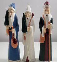 Front view of three carved wooden Santa Claus figures showing their colors and details