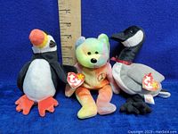 Three Ty Beanie Babies plush toys: Puffin, Peace Bear, Canadian Goose with tags, shown with ruler for size reference.