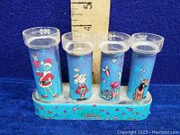 Front view showing four coin tubes with colorful Grinch Stole Christmas character illustrations and measurement scale