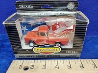 Front view showing orange wrecker truck in original box with partially torn front plastic