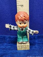 Front view of the vintage 1957 Goebel Hummel figurine showing the boy with outstretched arms standing on a soap box marked 'SCAP'. Ruler behind for size reference.