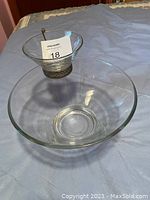 Clear glass chip and dip bowl with a brass dip bowl holder. The smaller dip bowl fits into a brass holder above the larger chip bowl, all made of clear glass except the brass holder.