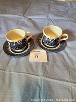 Two cups and two saucers with blue oriental motif decoration on white ceramic, marked Churchill England on bottom of cups, displayed on cloth surface with lot number.