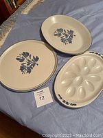 Photo showing three ceramic dishes: devilled egg plate with egg compartments and blue floral rim, round serving dish, and oval serving dish with blue floral designs.