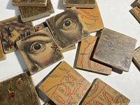 Close-up image of several wooden puzzle blocks showing detailed images of an eye and colorful anatomical sketches on block faces.