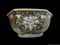 Close-up side view of the hand painted floral designs on the octagonal porcelain bowl against an olive green background.