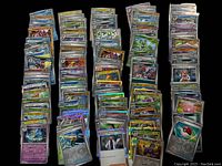 Stacks of sleeved holographic Pokemon cards arranged on black surface