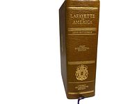 Photo of the book spine showing title, author, edition, and society emblem in gold embossing on brown leather.