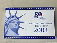 Front cover of the 2003 United States Mint Proof Set showing Statue of Liberty print and 50 State Quarters logo.