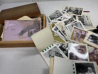 Wooden box containing military letters, cards, and loose photographs spread on surface